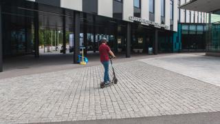 Ihminen ajaa sähköpotkulaudalla Vantaan Clarion-hotellin ohi isoilla noppakivillä päällystetyllä kadulla.